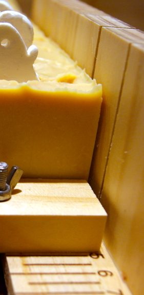 Gelber Seifenblock mit gewelltem Rand und Holzunterlage.