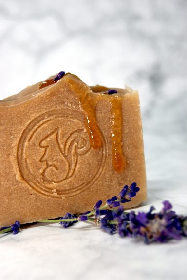 Seife mit Lavendelblüten und Honigtröpfchen, auf einem marmorierten Hintergrund.