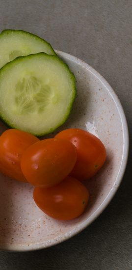 Runde, orange Tomaten und Gurkenscheiben auf einem Teller.