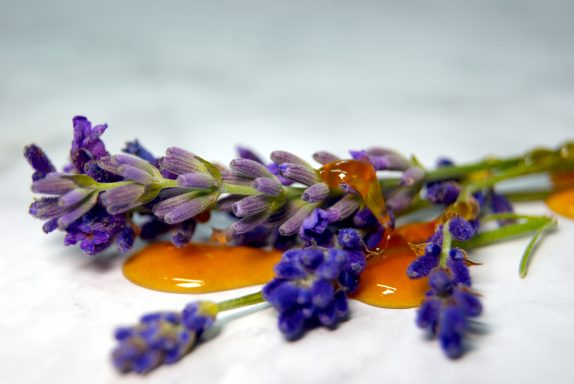 Lavendel - Honig Seife mit Lavendelblüten und Honigtröpfchen, auf einem marmorierten Hintergrund.