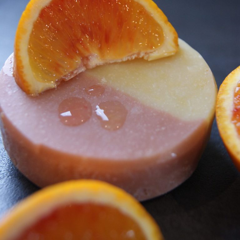 Zwei Schichten Seife in Rosa und Gelb, dekoriert mit Orangenscheiben.