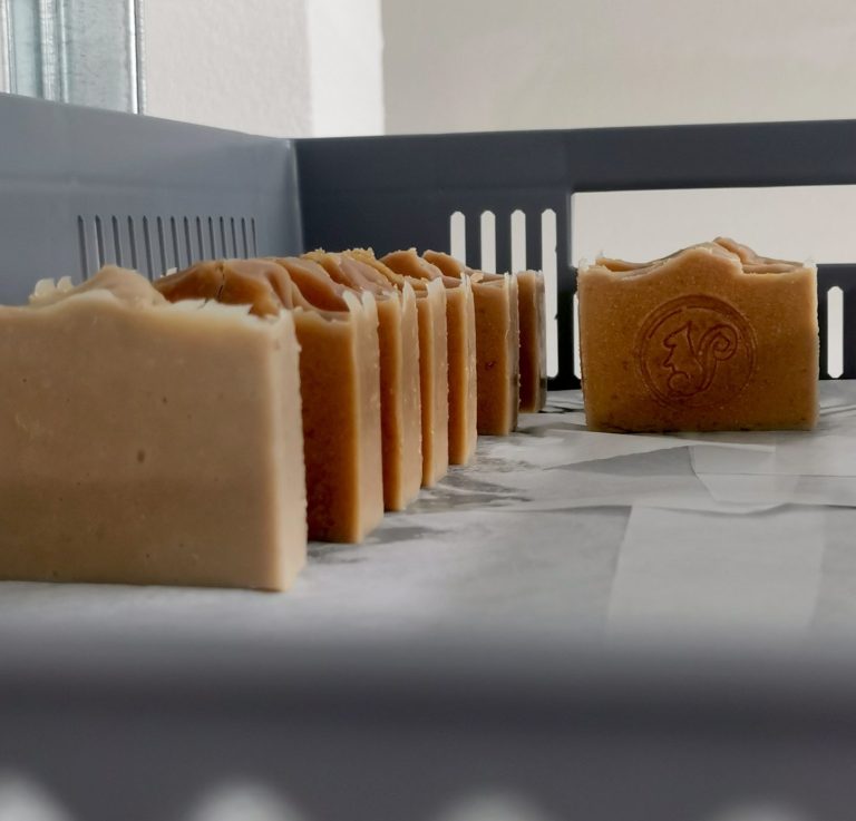 Seifenstücke in verschiedenen Farben und Formen auf einem Regal angeordnet.