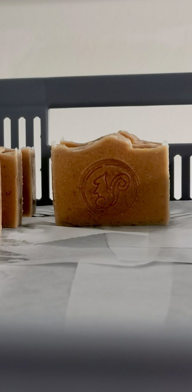 Gelber Seifenblock mit gewelltem Rand und Holzunterlage.